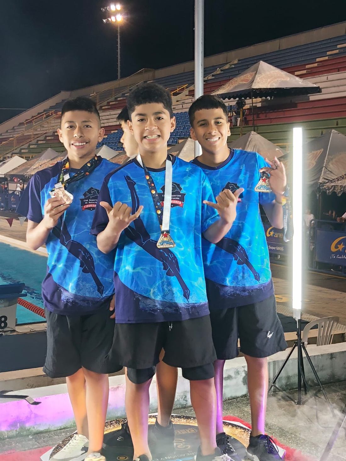Tres nadadores del club mostrando sus medallas