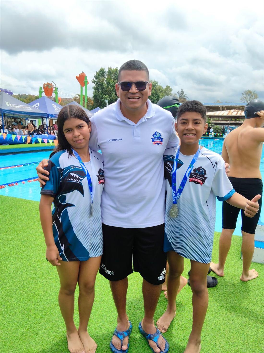Equipo Tiburones con la bandera del club junto a la piscina