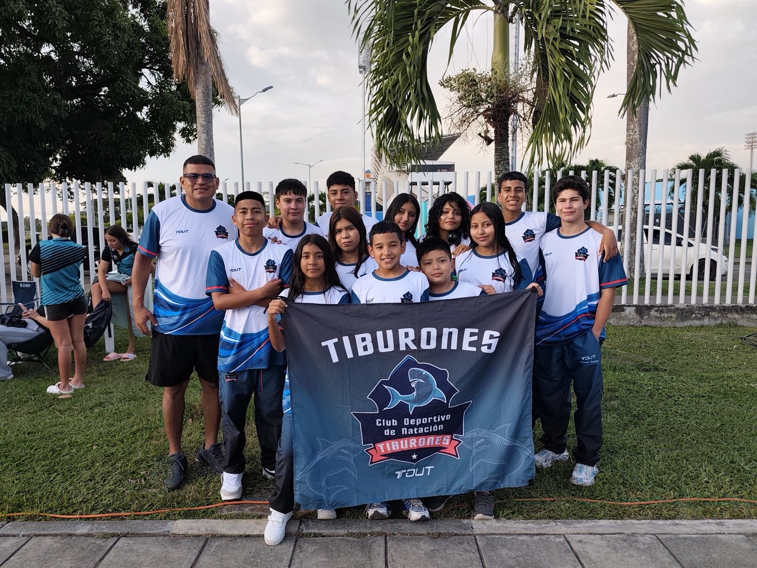 Equipo Tiburones junto a su entrenador sosteniendo la bandera del club
