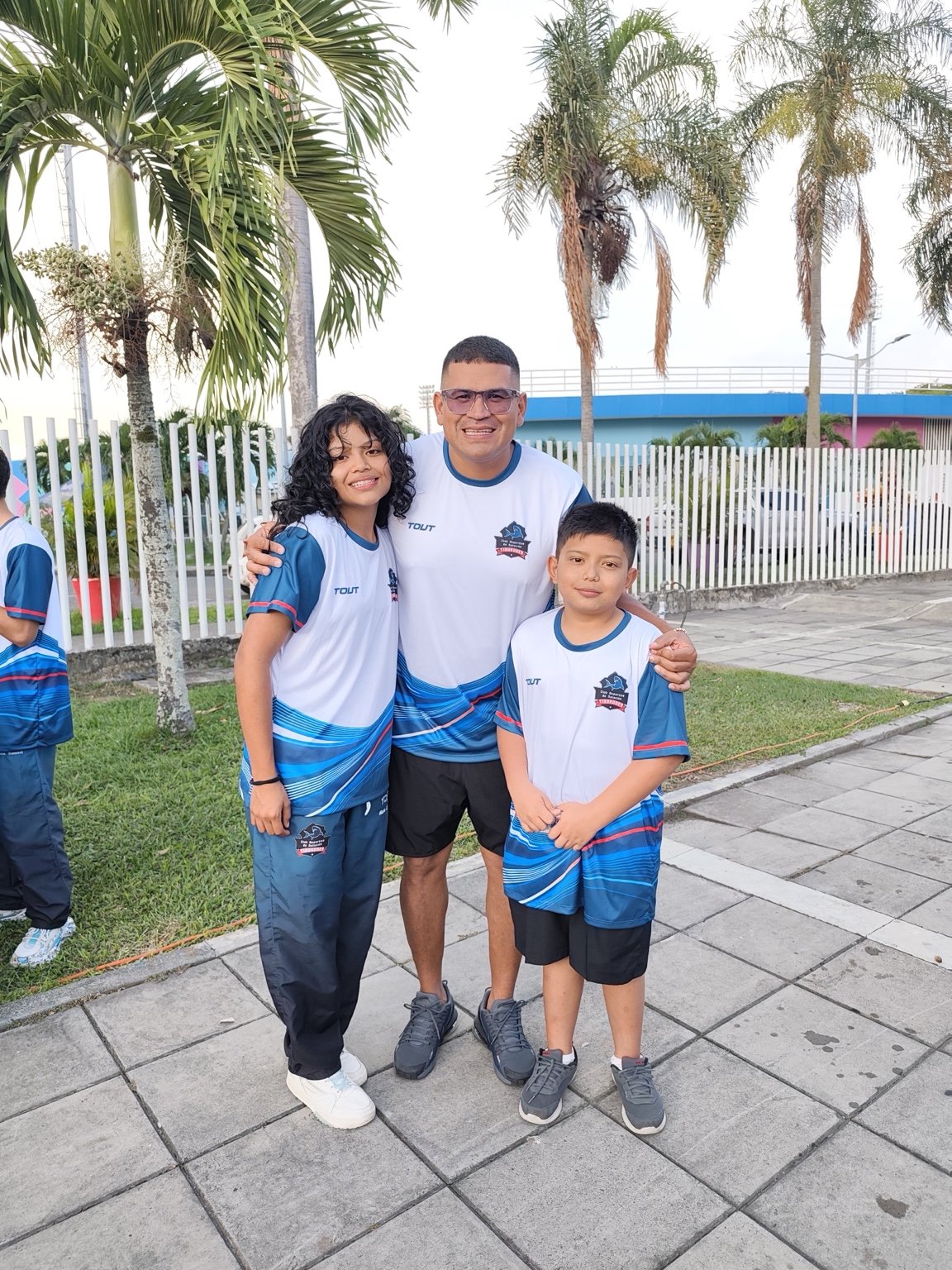 Entrenador de Tiburones junto a dos deportistas del equipo