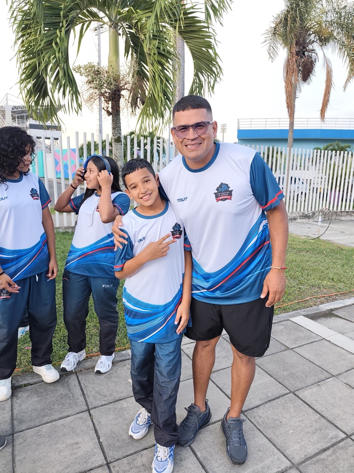 Nadadora de Tiburones y su entrenador posando con el uniforme del equipo
