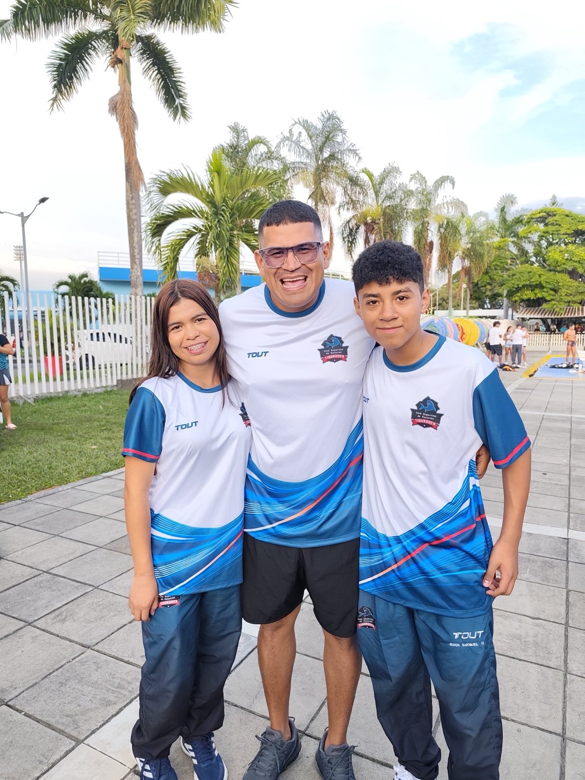 Entrenador de Tiburones acompañando a dos integrantes del equipo