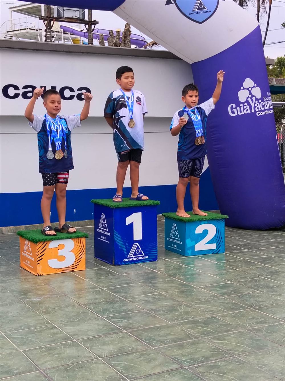 Podio de una competencia con tres nadadores del club celebrando