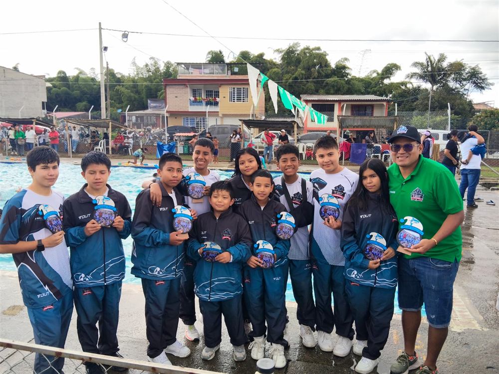 Equipo del club con sus medallas junto al entrenador, en un día de lluvia