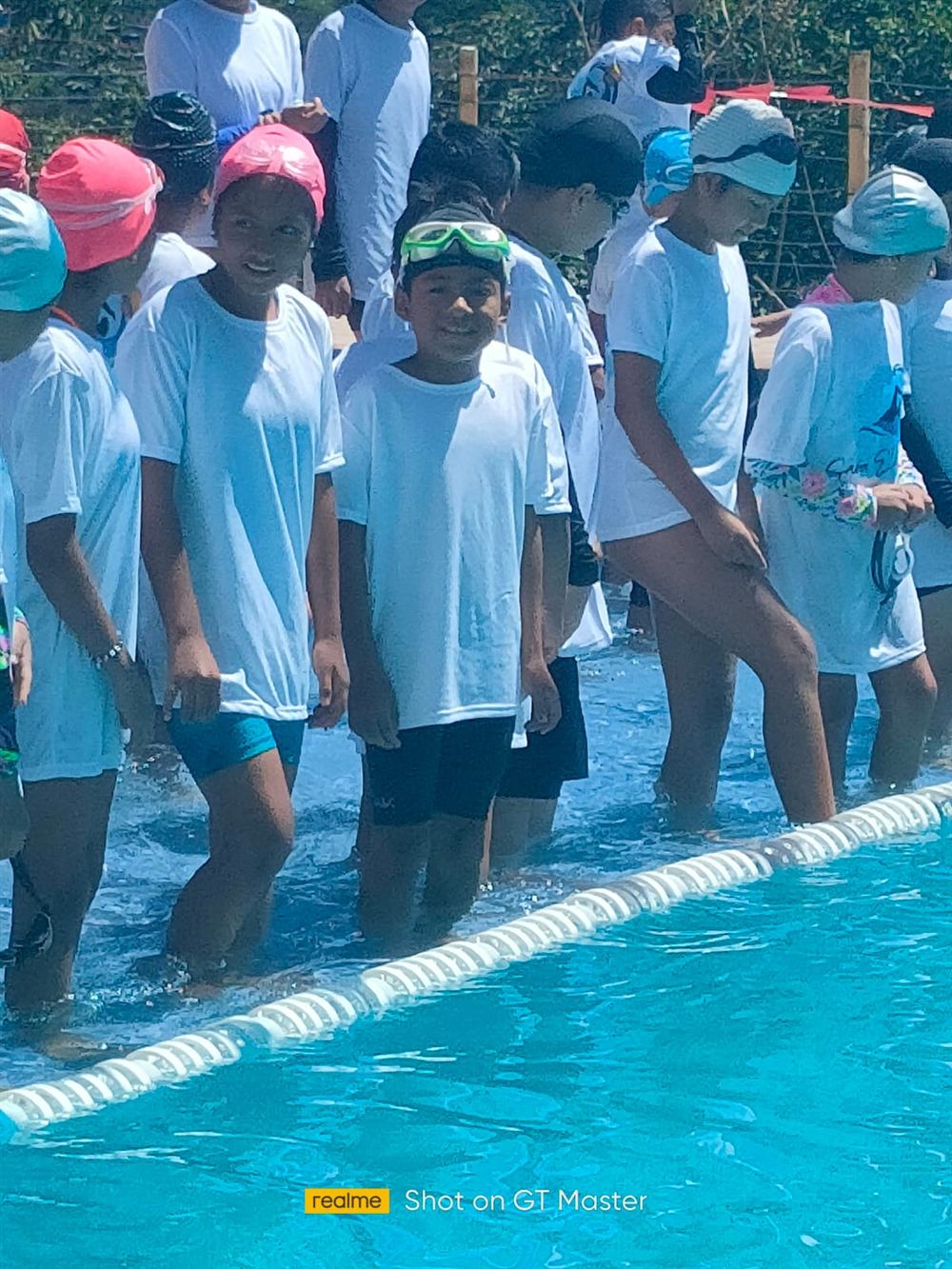 Nadadores del club junto a la piscina con gorros y antiparras
