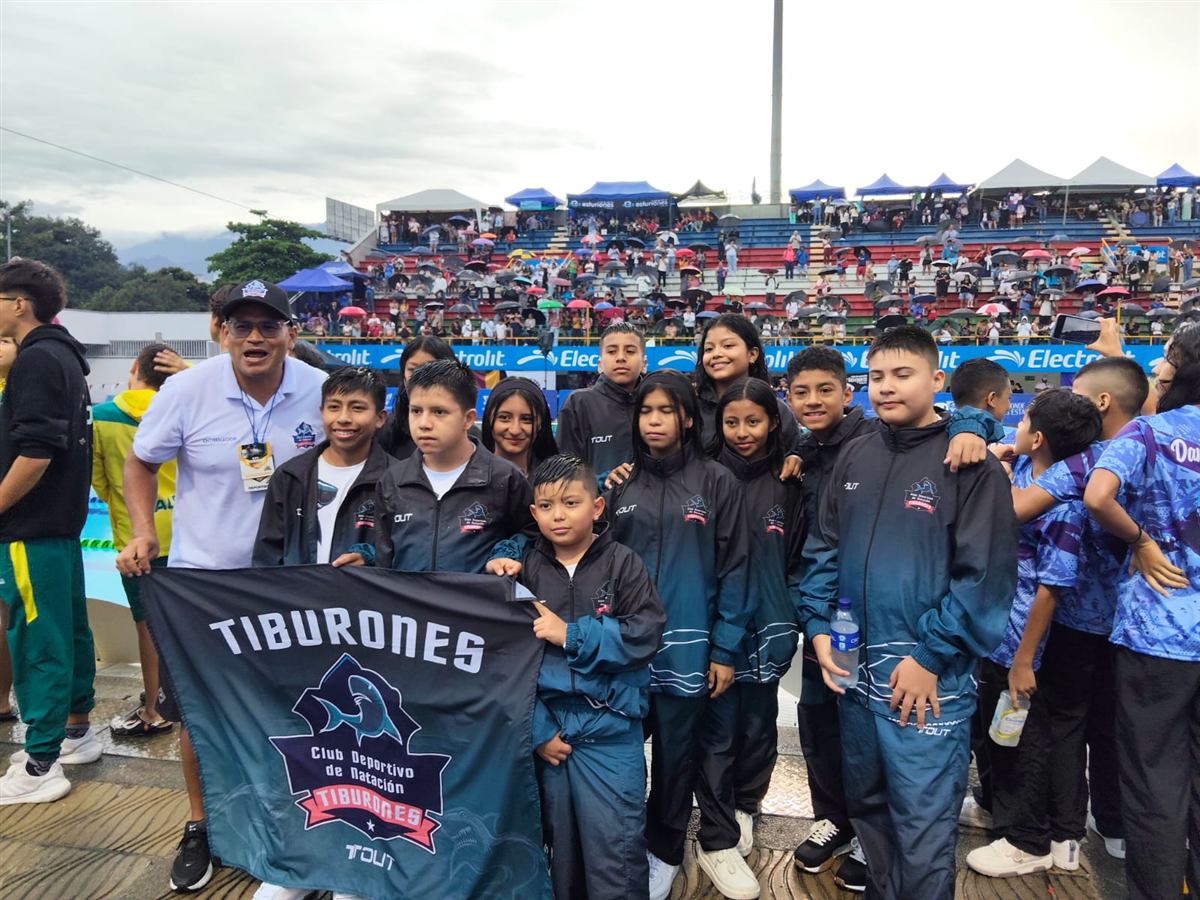 Equipo Tiburones sosteniendo la bandera del club en un torneo